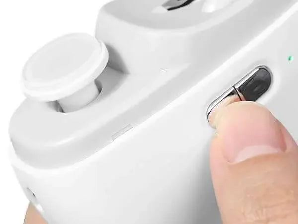 Close-up of finger pressing power button on white Electric USB Nail Trimmer with built-in LED light and ergonomic design