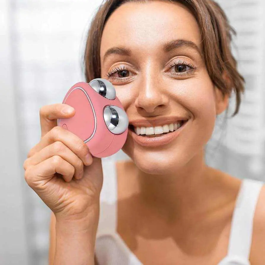 Woman using a pink microcurrent face lifting massager on her cheek for skin toning and rejuvenation