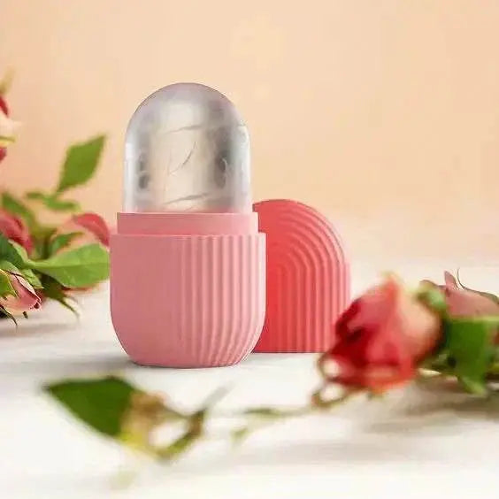 Pink silicone ice roller with clear freezing compartment for facial skincare on beige background with blurred flowers