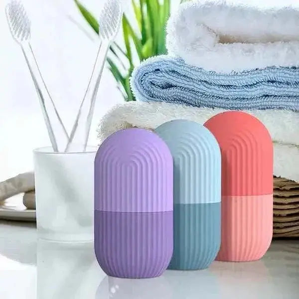 Compact silicone ice rollers for face skincare in pastel purple, blue, and coral colors on a bathroom counter with towels and toothbrushes.