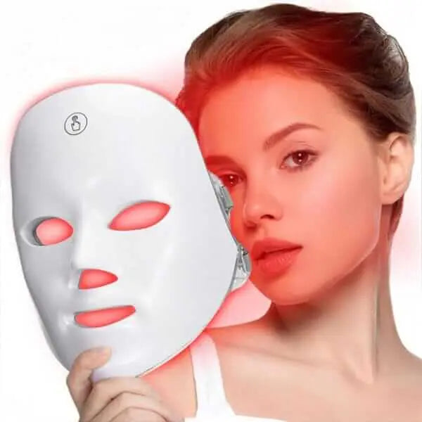 Woman holding a white Wireless LED Light Therapy Mask with red light glowing from the eye, nose, and mouth openings for face and neck skincare.